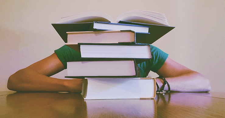 Reading Recommendations header image showing a person sitting behind a stack of books