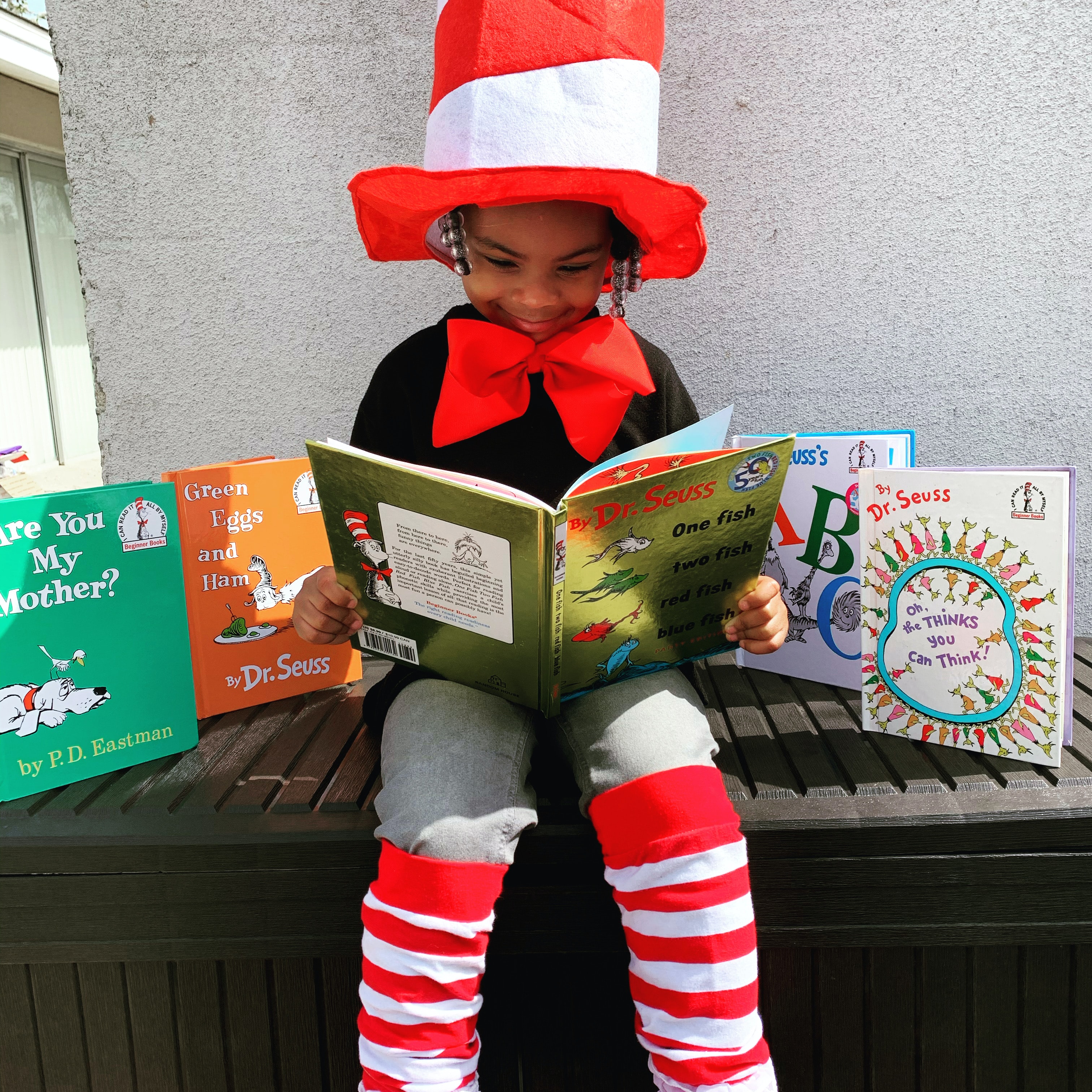 Young girl reading and dressed as the cat in the hat