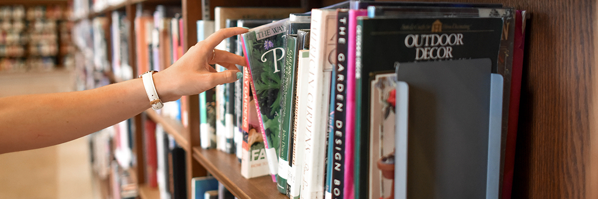 Borrowing header image showing an arm reaching forth and selecting a book from the book shelf