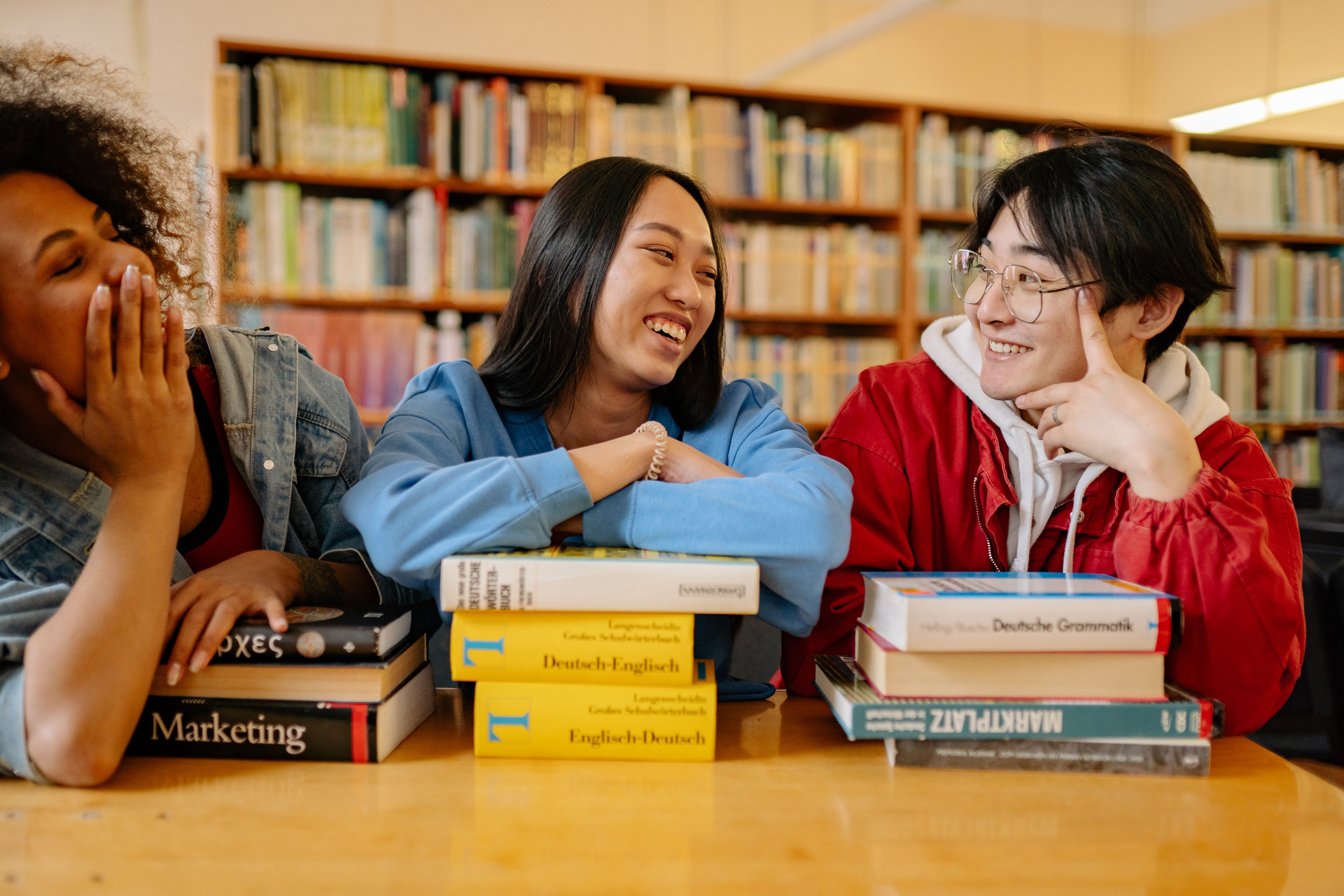 Three young people with stack of books in front of each of them