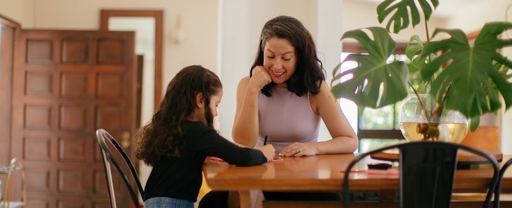 Woman reading to child at table. 