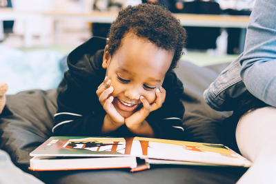 Young boy reading with smile on his face