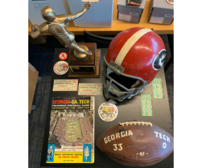 A photo displaying various sports memorabilia: a trophy, a football, a red helmet.
