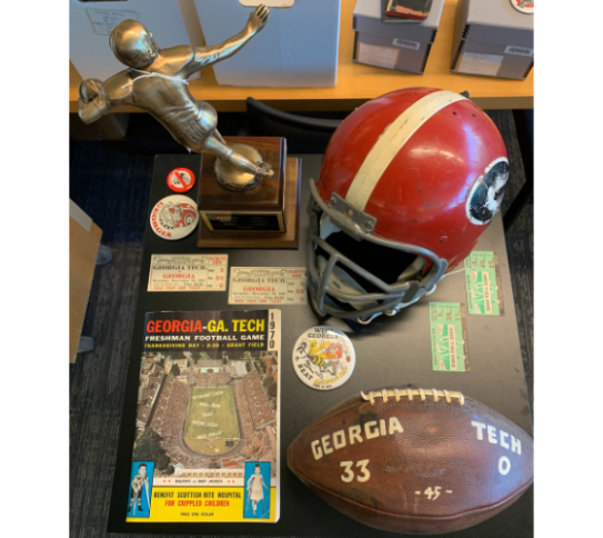 A photo displaying various sports memorabilia: a trophy, a football, a red helmet.  