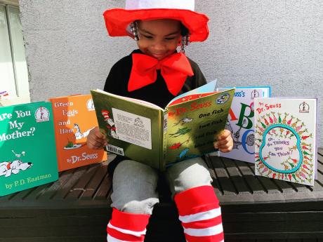 Young girl reading and dressed as the cat in the hat