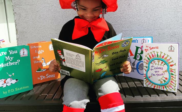 Young girl reading and dressed as the cat in the hat