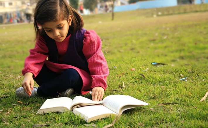 Young girl reading on grass